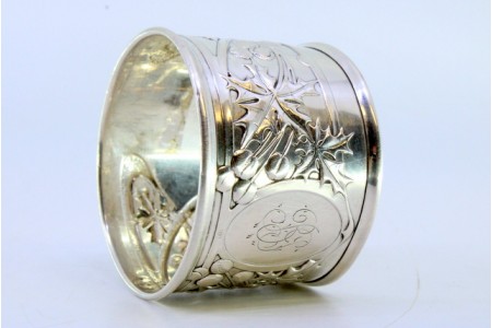  Argola de guardanapo em prata com flores e frutos relevados envolvendo cartela para monograma.